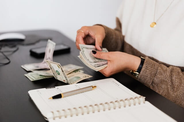 Qui suis-je ? crop payroll clerk counting money while sitting at table